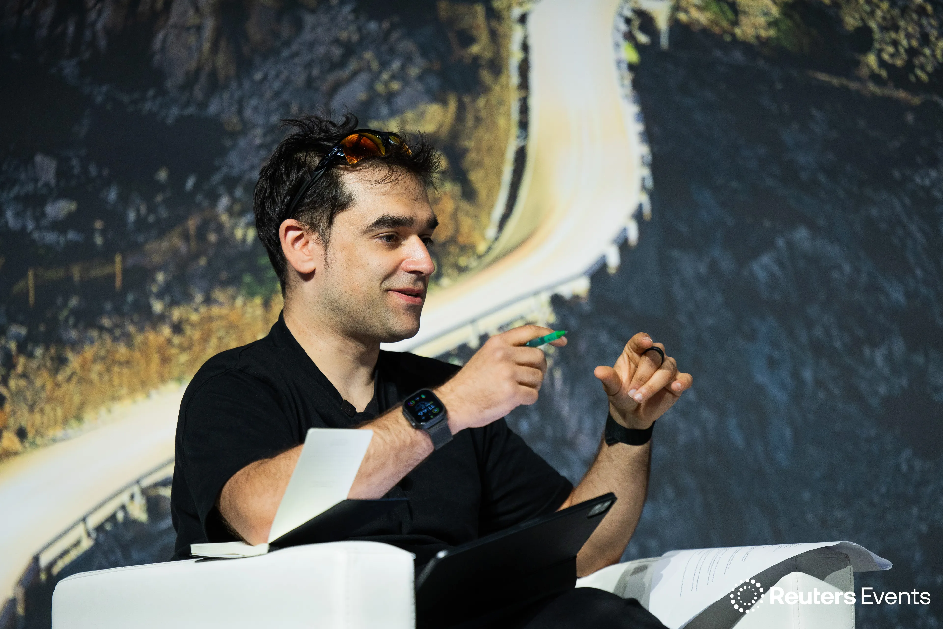 Dr Kishan Rees speaking on stage at a Reuters Events panel, gesturing mid-sentence.